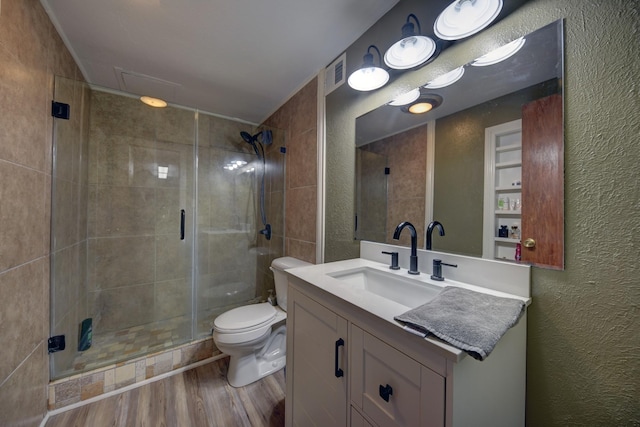 bathroom with a stall shower, a textured wall, toilet, wood finished floors, and vanity