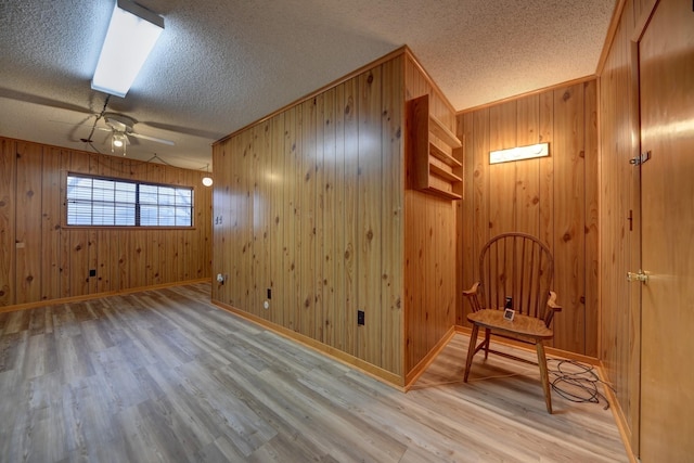 interior space featuring baseboards, a textured ceiling, a ceiling fan, and wood finished floors
