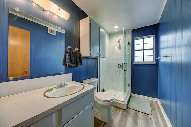 full bath featuring toilet, wood finished floors, visible vents, vanity, and a shower stall