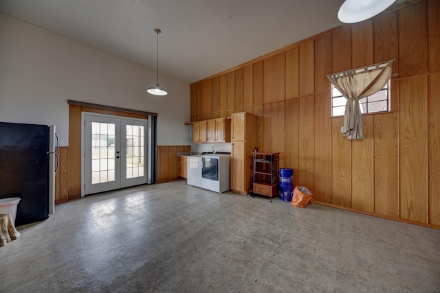 kitchen with washer and clothes dryer, decorative light fixtures, freestanding refrigerator, french doors, and wood walls