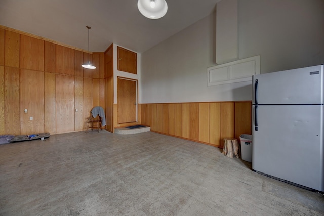 empty room with a wainscoted wall, wooden walls, and a towering ceiling