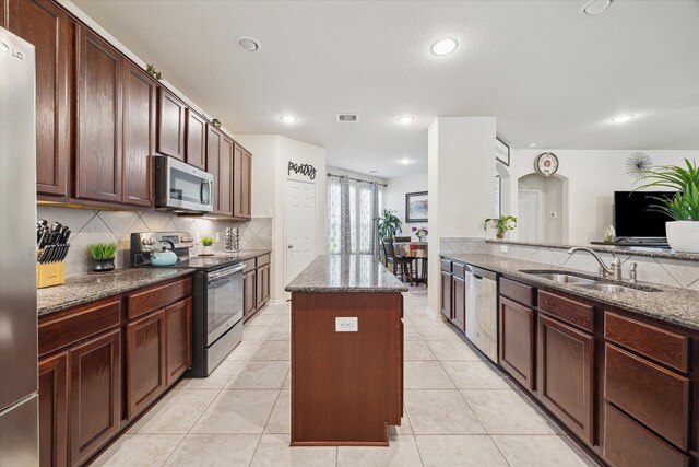 14510 Myers Dr, Houston, TX 77090 - kitchen with a center island, tasteful backsplash, a sink, stainless steel appliances, and dark stone counters
