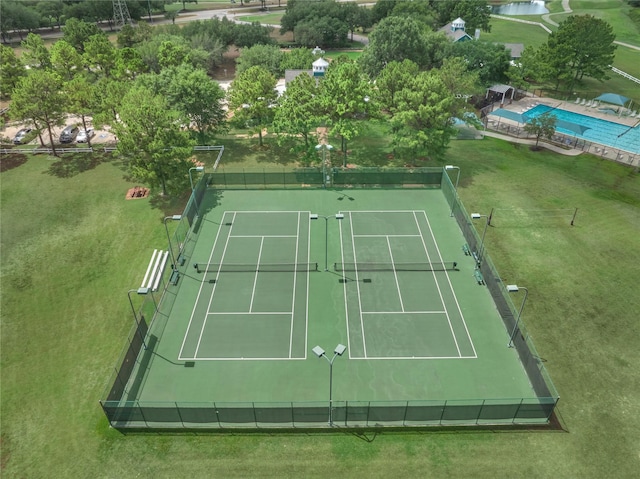 view of tennis court featuring a yard and fence