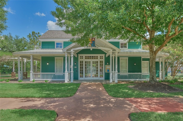 view of front of property featuring a front yard, covered porch, metal roof, and a standing seam roof