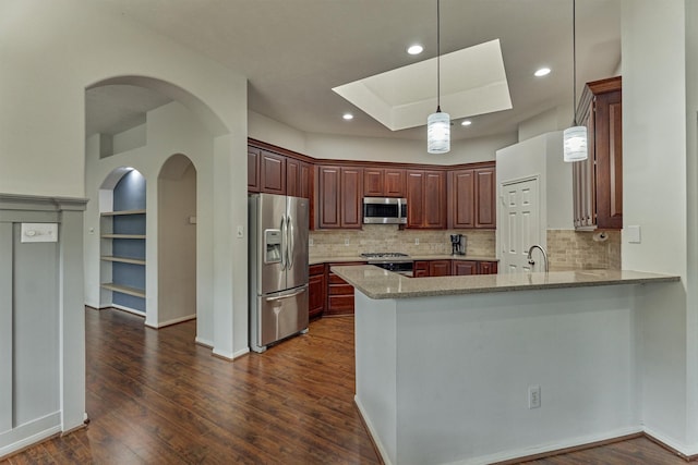 kitchen with a peninsula, dark wood-style floors, appliances with stainless steel finishes, and light stone countertops