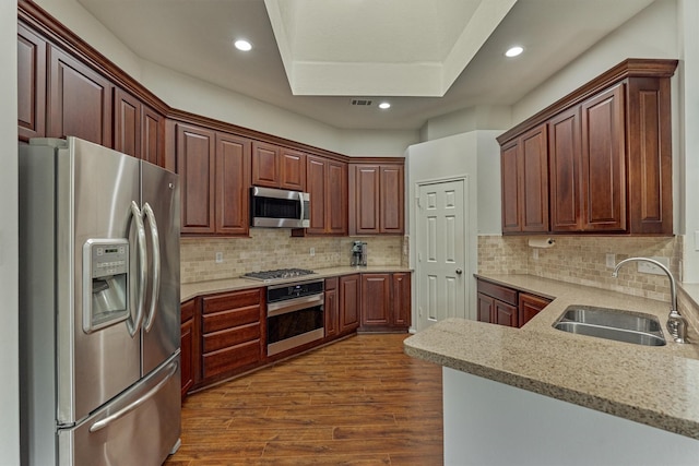 kitchen featuring recessed lighting, a sink, appliances with stainless steel finishes, tasteful backsplash, and dark wood finished floors