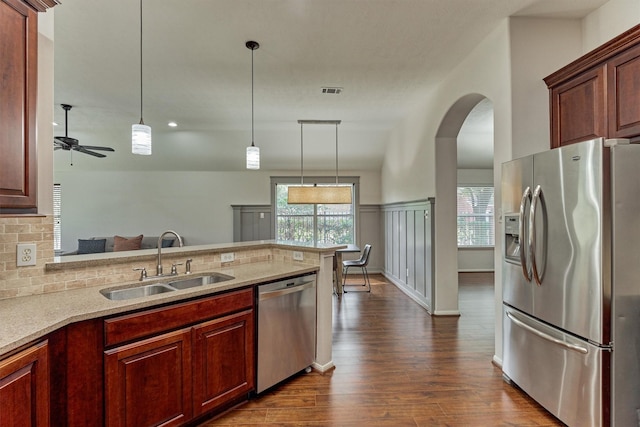 kitchen featuring appliances with stainless steel finishes, dark wood-style flooring, a sink, and pendant lighting