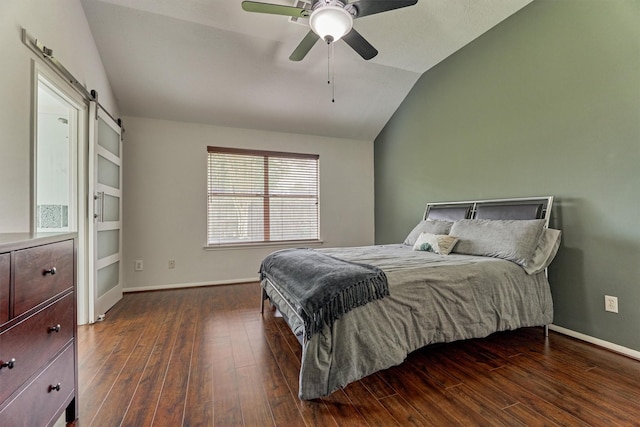 bedroom with vaulted ceiling, a barn door, dark wood-style flooring, and baseboards