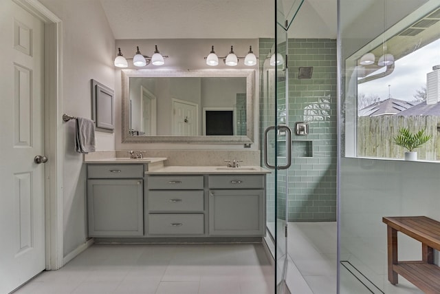 full bathroom featuring double vanity, tile patterned flooring, a shower stall, and a sink