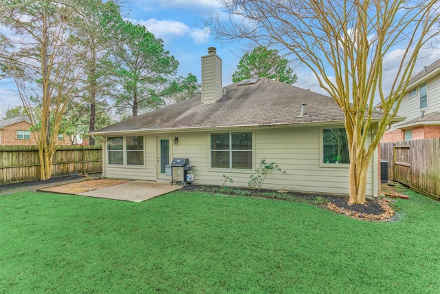 rear view of property featuring a fenced backyard, a chimney, roof with shingles, a yard, and a patio area