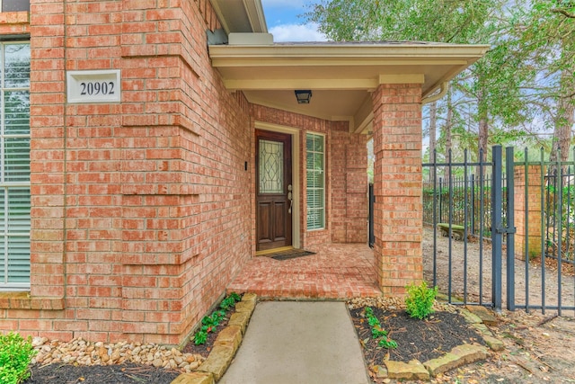 property entrance with brick siding, fence, and a gate