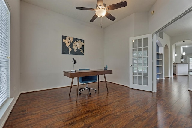 office space with arched walkways, ceiling fan, hardwood / wood-style flooring, and baseboards