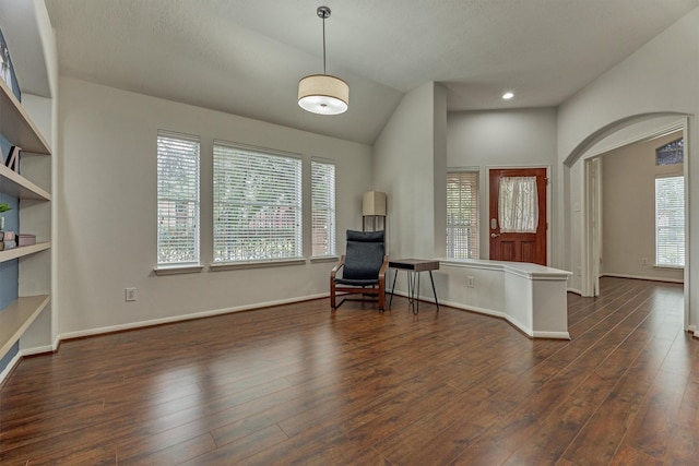 unfurnished room with a wealth of natural light, arched walkways, wood-type flooring, and baseboards