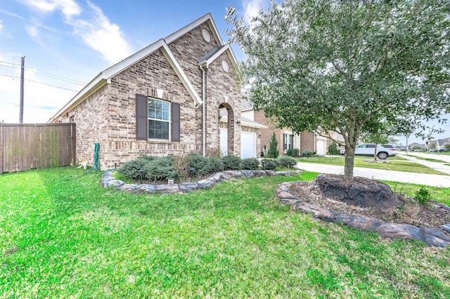 view of front of home with concrete driveway, brick siding, a front lawn, and fence