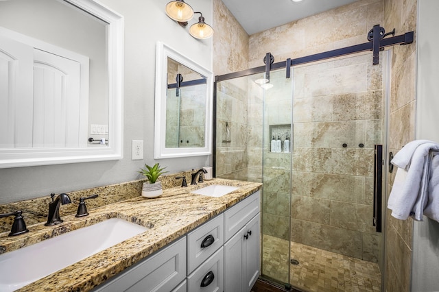 bathroom with a stall shower, a sink, and double vanity