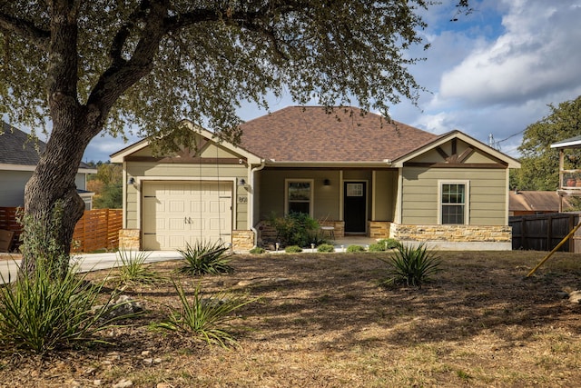 view of front of home with stone siding, fence, driveway, and an attached garage