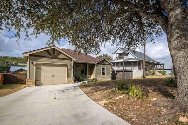 view of front of house featuring a garage, stone siding, fence, and concrete driveway