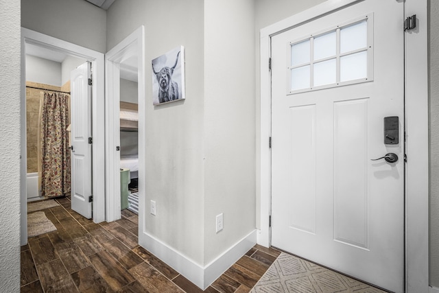 foyer entrance with baseboards and wood finish floors