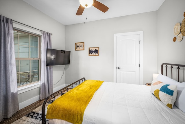 bedroom with a ceiling fan, wood finished floors, and baseboards