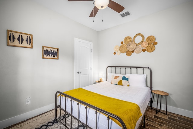 bedroom with a ceiling fan, visible vents, baseboards, and wood finished floors