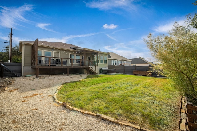 rear view of house featuring fence, a wooden deck, and a lawn