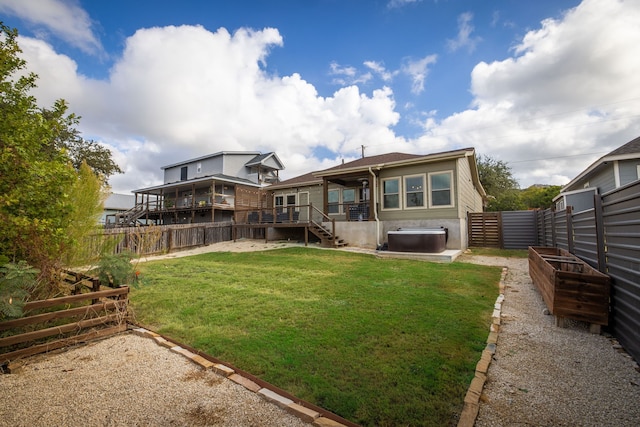 rear view of house with a lawn, a wooden deck, and a fenced backyard