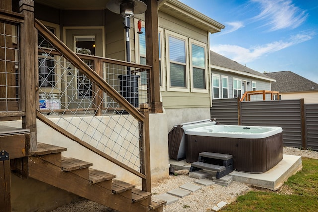 exterior space featuring cooling unit, a hot tub, and stucco siding