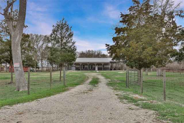 view of front of house with a front lawn, covered porch, fence, and dirt driveway