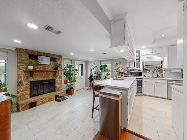 kitchen with a fireplace, light countertops, visible vents, a sink, and beverage cooler