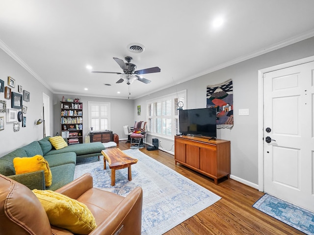 living room featuring ornamental molding, visible vents, baseboards, and wood finished floors