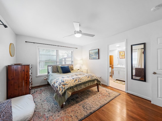 bedroom with a ceiling fan, ensuite bath, light wood-style flooring, and baseboards