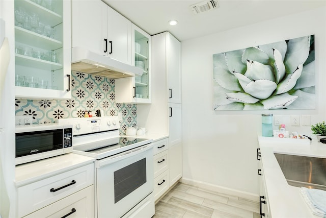 kitchen with under cabinet range hood, white appliances, a sink, visible vents, and tasteful backsplash