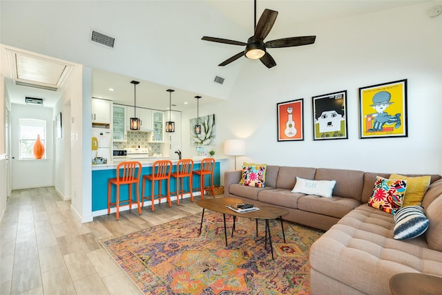 living room with high vaulted ceiling, light wood finished floors, visible vents, and a ceiling fan