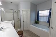 full bathroom with a garden tub, a shower stall, and vanity