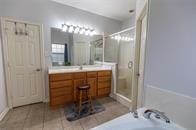 bathroom featuring a stall shower, tile patterned flooring, a tub, and vanity