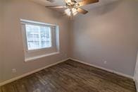 unfurnished room with wood finished floors, a ceiling fan, and baseboards