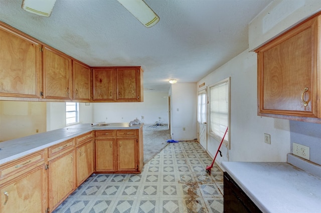 kitchen with brown cabinets, light floors, light countertops, and a textured ceiling