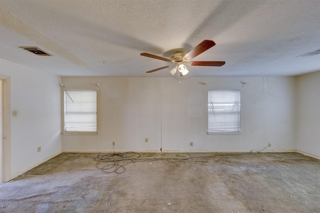 spare room with a textured ceiling, ceiling fan, and visible vents