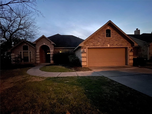 view of front of property with brick siding, driveway, a front yard, and a garage