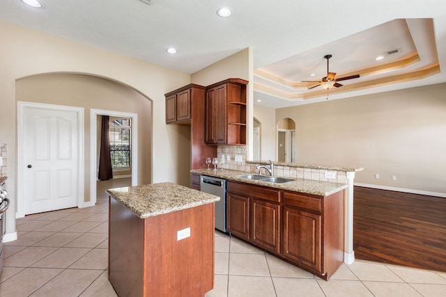 kitchen with open shelves, arched walkways, a sink, dishwasher, and a raised ceiling