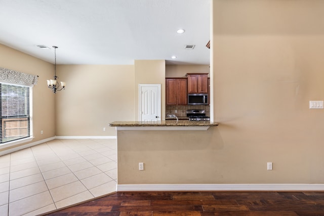 kitchen featuring visible vents, an inviting chandelier, stone countertops, appliances with stainless steel finishes, and backsplash