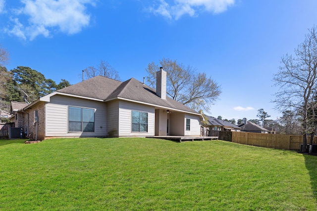 back of house with brick siding, fence, a chimney, a deck, and a yard