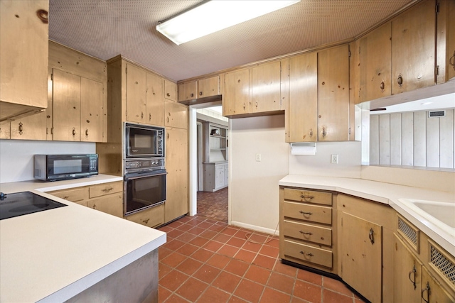 kitchen with black appliances, light countertops, a sink, and dark tile patterned flooring