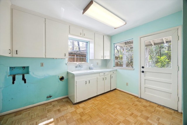 washroom with washer hookup, cabinet space, baseboards, and a sink