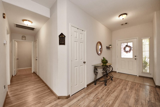 foyer entrance with light wood-style floors, baseboards, and visible vents