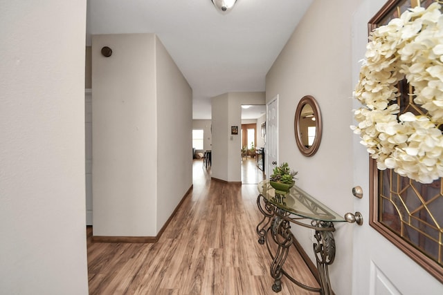 hall with light wood-type flooring and baseboards