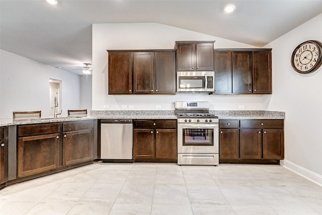 kitchen with light stone counters, appliances with stainless steel finishes, vaulted ceiling, a sink, and dark brown cabinetry