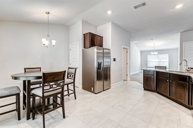 kitchen with stainless steel refrigerator with ice dispenser, a sink, visible vents, and a notable chandelier