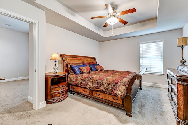 bedroom with carpet floors, visible vents, a tray ceiling, and baseboards