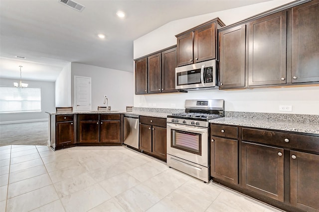 kitchen with dark brown cabinetry, visible vents, light stone countertops, stainless steel appliances, and a sink